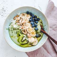 Coconut matcha yogurt bowl with blueberries, banana, kiwi fruit and nuts